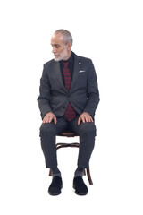 front view of a man sitting  on chair with suit and tie and  looking down on white background