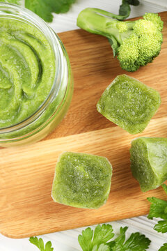 Frozen broccoli puree cubes and ingredient on cutting board, flat lay