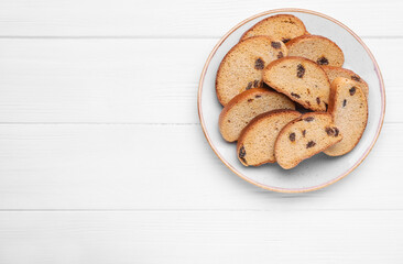 Plate of sweet hard chuck crackers with raisins on white wooden table, top view. Space for text