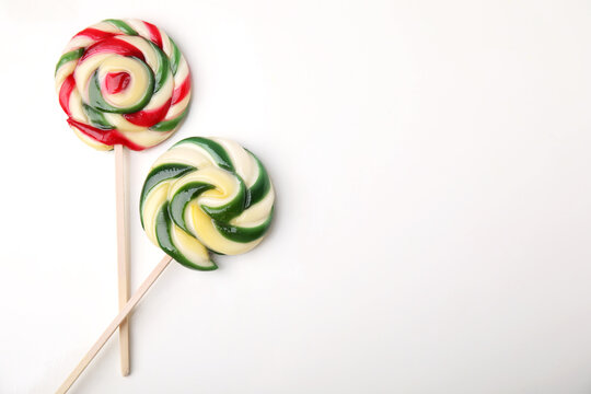 Colorful lollipops on white background, flat lay. Space for text
