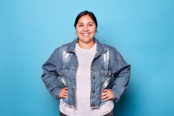 Young curvy Latina woman wearing a denim jacket and hoop earrings, smiling and looking at the...