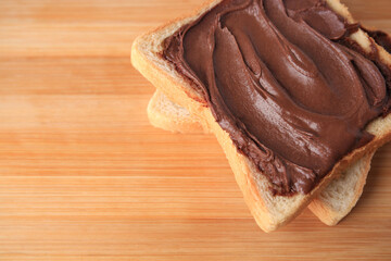 Tasty toast with chocolate paste on wooden table, above view. Space for text