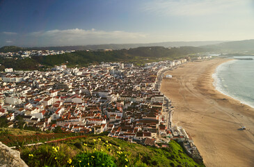 View Nazare beach riviera with cityscape of Nazare town at sunny weather. Portugal. High quality photo