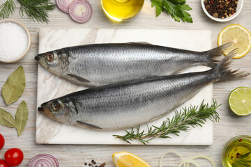 Delicious salted herrings and different ingredients on light wooden table, flat lay
