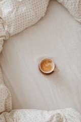 Cozy unmade bed with a coffee cup in the morning, breakfast in bed