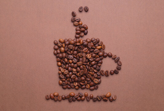 Cup of hot drink, composition made with coffee beans on brown background, flat lay