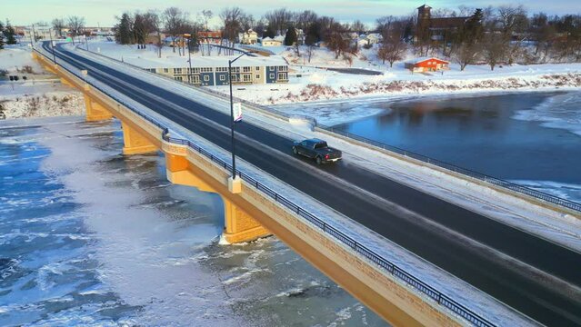 Scenic bridge over ice covered river in Winter, moving aerial view.
