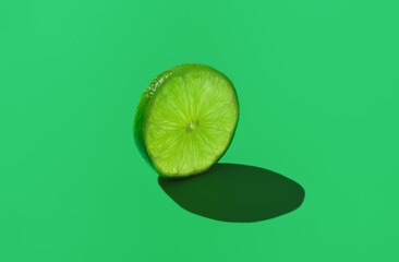 Lime slice isolated on a green background.