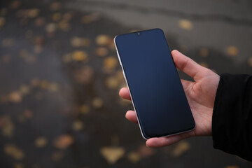 Woman holding phone outdoors on rainy day, closeup. Space or text