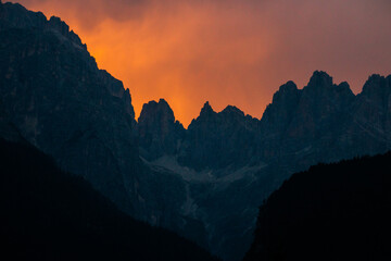 Silhouette of some mountains with a beautiful sunset and orange sky in the Dolomites, Italy. Concept of nature, mountains, mountaineering and travel.
