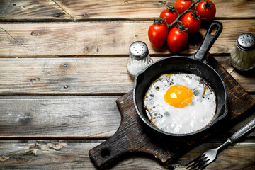 Fried egg in a pan with tomatoes.