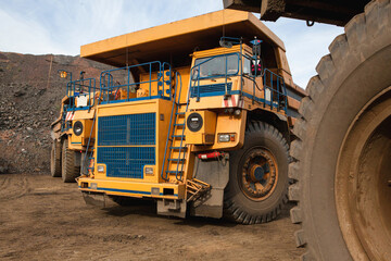 Large yellow dump trucks engaged in the transportation of rock mass in the quarry for mining. Machinery and equipment for iron ore mining