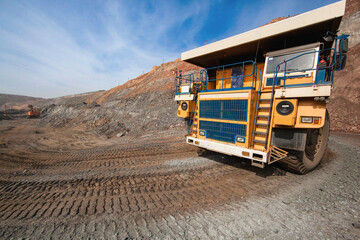 Large yellow dump truck engaged in the transportation of rock mass in the quarry for mining. Machinery and equipment for iron ore mining