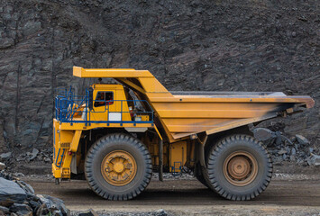 Large yellow dump trucks engaged in the transportation of rock mass in the quarry for mining. Machinery and equipment for iron ore mining