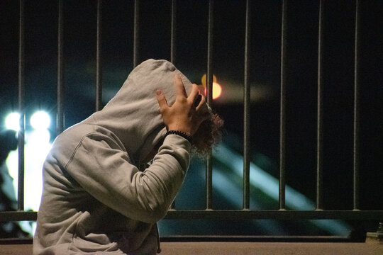 curly guy in the grey hoodie is standing against the cell of the traffic road 