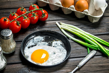 Fried egg in a pan with a cassette of fresh eggs.