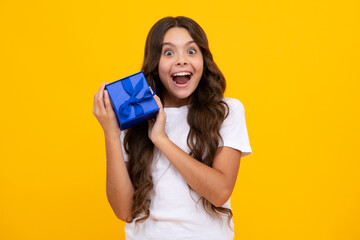 Amazed teen girl. Emotional teenager child hold gift on birthday. Funny kid girl holding gift boxes celebrating happy New Year or Christmas. Excited expression, cheerful and glad.