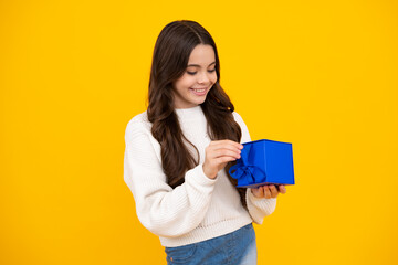 Happy face, positive and smiling emotions of teenager girl. Teenager child holding gift box on yellow isolated background. Gift for kids birthday. Christmas or New Year present box.