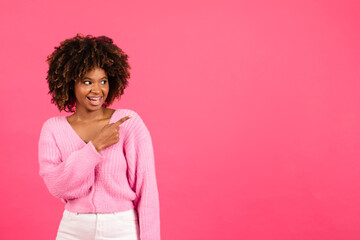 Smiling millennial african american curly lady in casual with braces, open mouth point finger at empty space