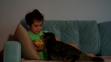 boy eats chips and watches TV at home with curiosity. Leisure time for children watching TV. Fast food. Fatty food.