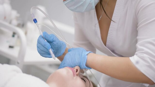 cosmetologist performs a gas-liquid peeling procedure - rejuvenation and regeneration of the skin using a jet consisting of oxygen and liquid.