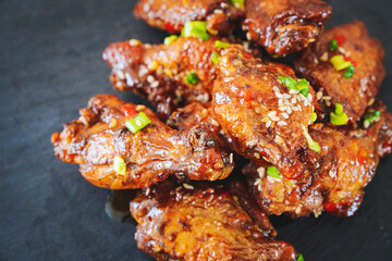 fried chicken with garlic and sesame in caramel on a black tray.