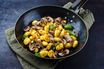 Traditional Italian gnocchi di patate with mushrooms as close-up in a frying pan with copy space