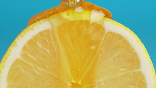 Macro texture shot of honey dripping down a fresh lemon slice on blue background.