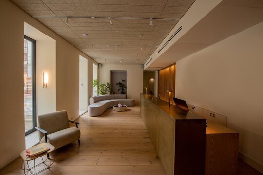 interior of luxury hotel lobby with reception desk near modern sofa and armchair.