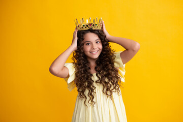 Teenage selfish girl celebrates success victory. Teen child in queen crown isolated on yellow...