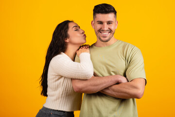 Smiling handsome millennial middle eastern woman kissing tall boyfriend on cheek, have fun together