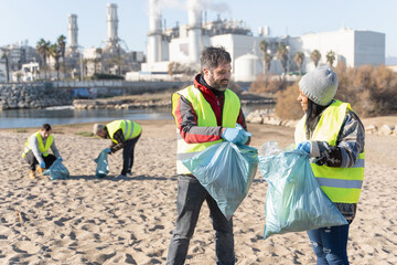Two volunteers cleaning beach from plastic rubbish. Man woman collecting garbage for Environment...