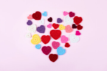 Multicolored crocheted hearts are laid out in the shape of a heart on a lilac background. Happy Valentine's Day, Mother's Day and birthday greeting card.