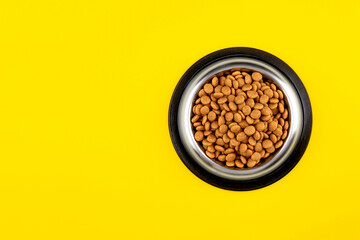 Food for cats and dogs in a bowl on a yellow background.Top view.Copy space.