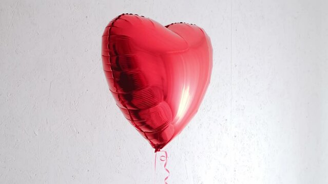 One beautiful big red heart shaped balloon with ribbon isolated on a white background. Beautiful birthday party gift. Floating object. Inflatable ball by helium gas. Valentines day gift. Love symbol.