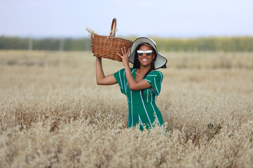 happy young woman walking in summer field wearing hat and sunglasses