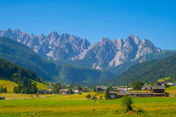 Panoramic view of idyllic mountain scenery in the Alps with fresh green meadows in bloom on a beautiful sunny day in springtime