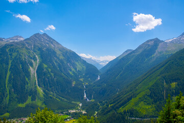Obraz premium Panoramic view of idyllic mountain scenery in the Alps with fresh green meadows in bloom on a beautiful sunny day in springtime