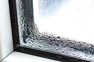 Water condensate drops on window glass.Drops of condensate and black mold on a substandard metal-plastic window.Concept:temperature difference, cooling, humidity in the room.Plastic. Ecology