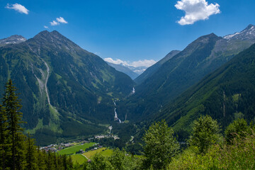 Obraz na płótnie Canvas Panoramic view of idyllic mountain scenery in the Alps with fresh green meadows in bloom on a beautiful sunny day in springtime