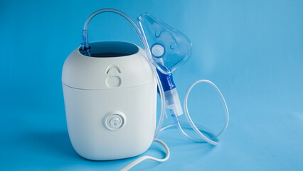 Medical equipment for inhalation with respiratory mask, nebulizer on a blue background.