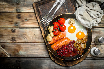 English breakfast.Fried eggs with sausages, bacon and red canned beans.