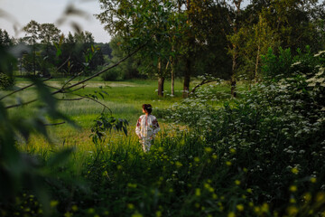 Beautiful girl in national clothes outdoors on the background of a green field and trees