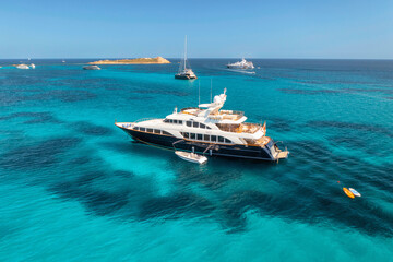 Aerial view of luxury yacht on blue sea at sunny day in summer. Sardinia, Italy. Aerial view of speed boats, yachts, sea lagoon, shore, transparent water, sky. Top view from drone. Tropical seascape © den-belitsky
