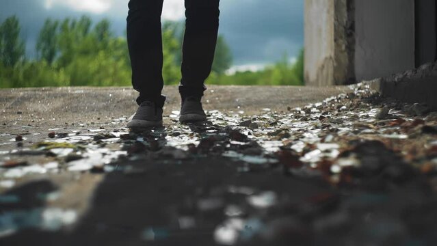 A man walks on a dirty roof and throws garbage around with his feet. Shooting close-up in slow motion