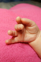 The baby's hand rests on a pink pillow in the shape of a heart.