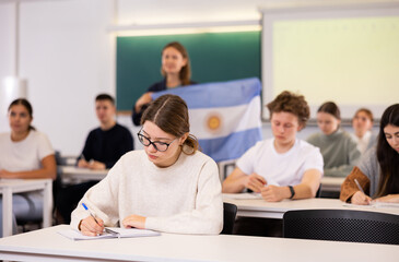 Fototapeta premium Young female student attentively listening to a lecture in a classroom