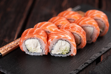 Sushi roll philadelphia with salmon and cucumber and cream cheese on black background close-up. Sushi menu. Japanese food concept