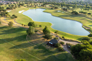 Aerial top view of a green park on the coast of lake. The water in the lake air shooting from the sky, lots of plants and trees.