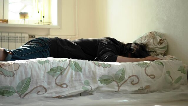From the fall of the guy on the mattress, dust rises in the room. the guy falls on the bed in slow motion